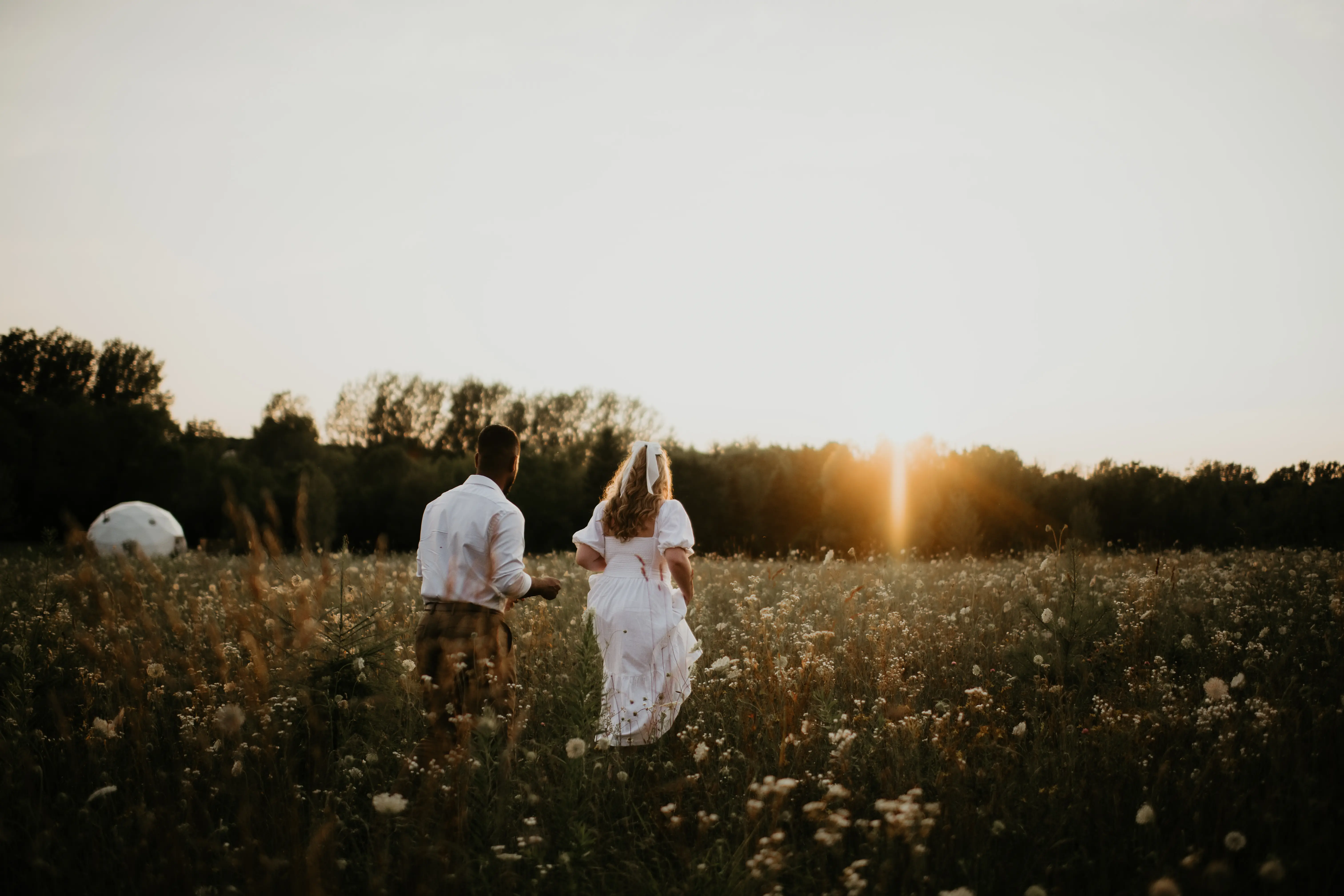 Couple Walking Through The Meadow At Sunset